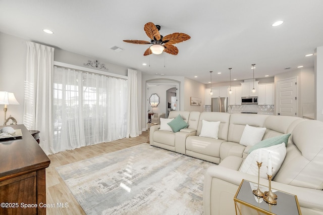 living area featuring recessed lighting, visible vents, arched walkways, light wood-type flooring, and ceiling fan