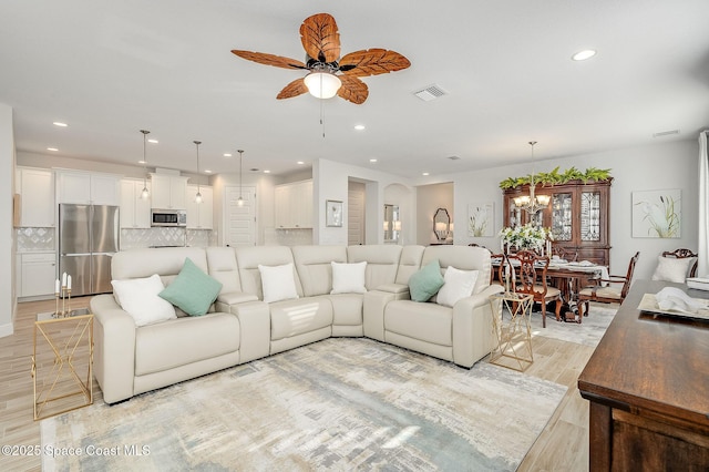 living area with recessed lighting, light wood-style flooring, visible vents, and ceiling fan with notable chandelier