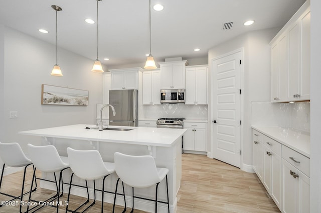 kitchen featuring recessed lighting, stainless steel appliances, a sink, a center island with sink, and a kitchen bar