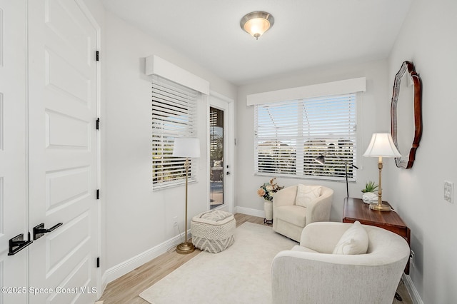 living area with light wood-type flooring and baseboards