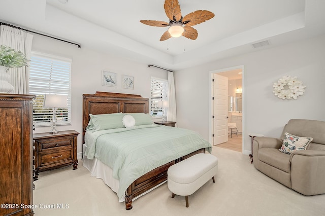 bedroom with baseboards, visible vents, ceiling fan, ensuite bath, and a raised ceiling