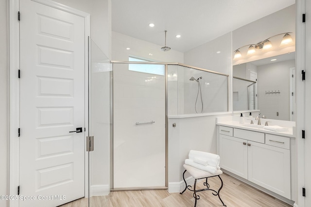 bathroom with a shower stall, vanity, wood finished floors, and recessed lighting