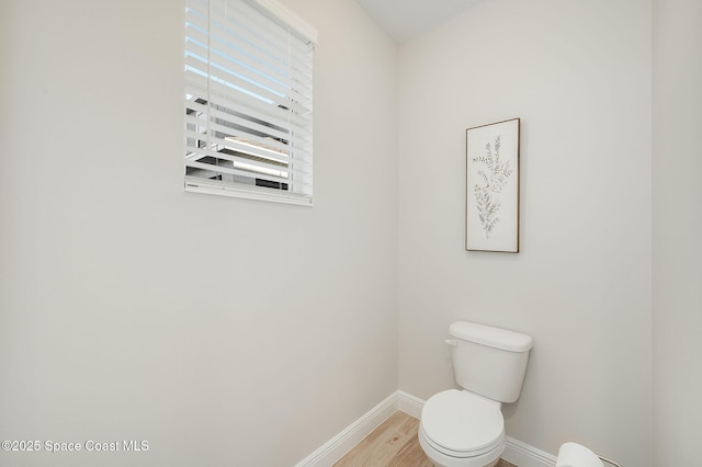 bathroom featuring wood finished floors, baseboards, and toilet