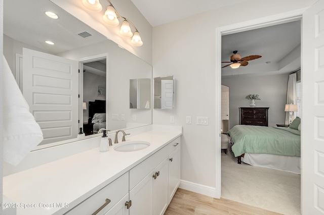 bathroom with wood finished floors, a ceiling fan, vanity, baseboards, and ensuite bathroom