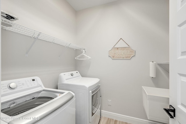 laundry room with washing machine and clothes dryer, baseboards, laundry area, and light wood-type flooring