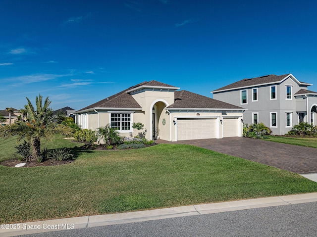 mediterranean / spanish-style house with roof with shingles, driveway, a garage, a front yard, and stucco siding