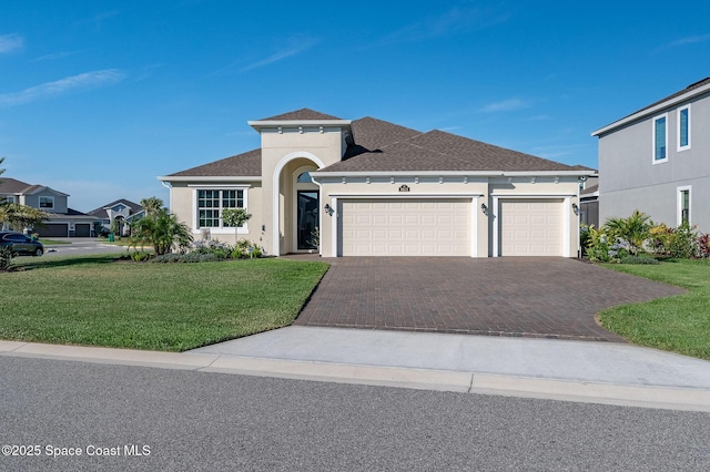 mediterranean / spanish home featuring an attached garage, a front yard, stucco siding, and decorative driveway