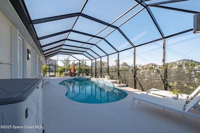 view of pool featuring a lanai, a pool with connected hot tub, and a patio