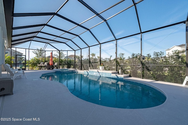 view of pool with a patio area, glass enclosure, and a pool with connected hot tub