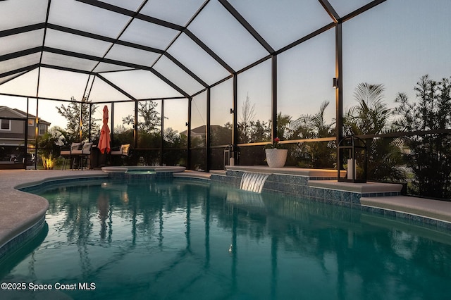 pool at dusk with a pool with connected hot tub, a lanai, and a patio