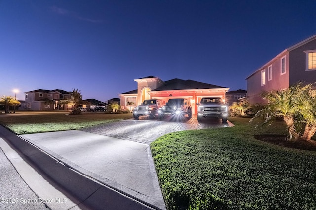 mediterranean / spanish home with an attached garage, driveway, and a front lawn