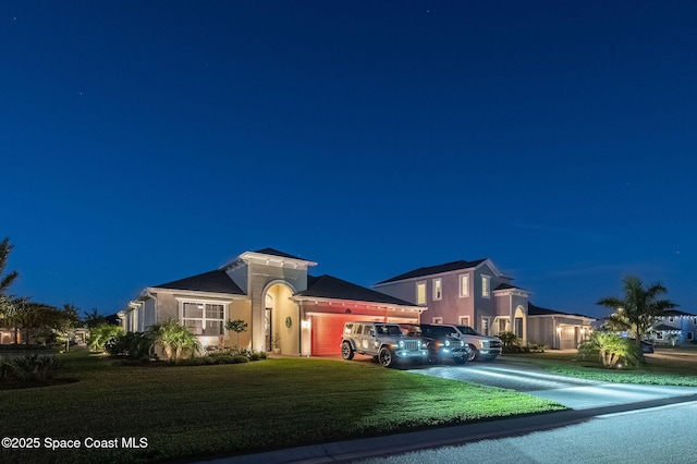 mediterranean / spanish-style home with an attached garage, driveway, and a yard