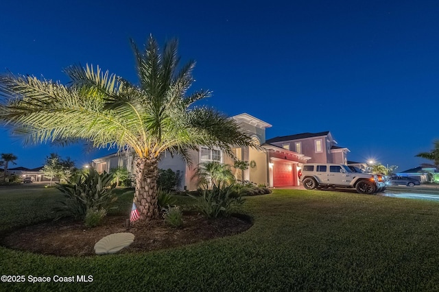 view of front of home with a garage, a lawn, and stucco siding