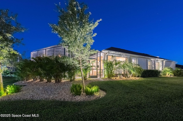 exterior space featuring a lawn, a lanai, and stucco siding