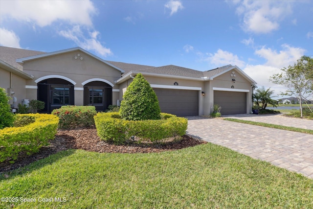 ranch-style home featuring driveway, a front lawn, a garage, and stucco siding