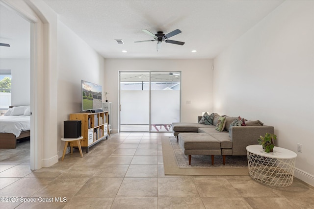 living area with light tile patterned floors, visible vents, baseboards, and a ceiling fan
