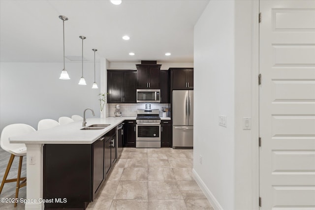 kitchen with tasteful backsplash, a sink, light countertops, a kitchen bar, and stainless steel appliances