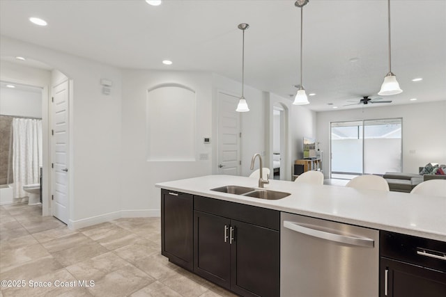 kitchen featuring hanging light fixtures, a sink, open floor plan, light countertops, and stainless steel dishwasher