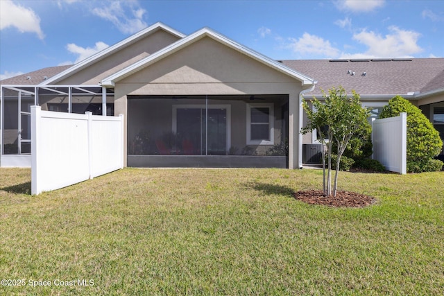 back of property featuring a yard, fence, a sunroom, and stucco siding