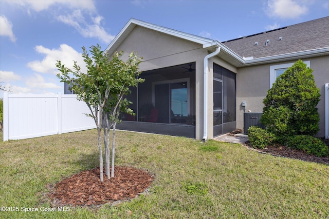 back of property featuring a sunroom, stucco siding, and a lawn