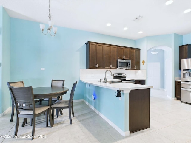 2515 SE Marquez Ave SE, Palm Bay, FL 32909 - kitchen with dark brown cabinetry, arched walkways, appliances with stainless steel finishes, light countertops, and backsplash