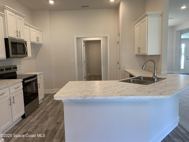 2205 Sans Souci Ave SE, Palm Bay, FL 32909 - kitchen with stainless steel appliances, a peninsula, dark wood-type flooring, white cabinetry, and recessed lighting