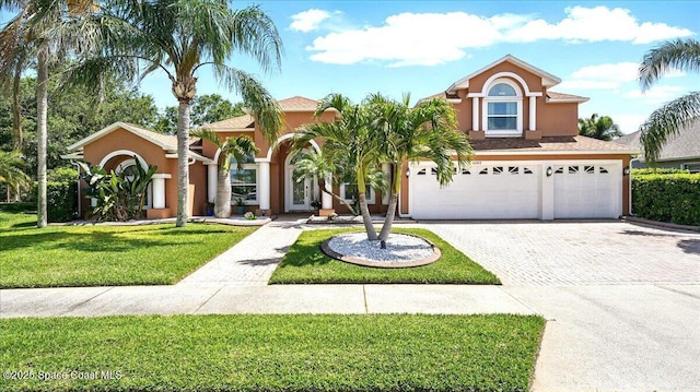 mediterranean / spanish home featuring a garage, a front yard, driveway, and stucco siding