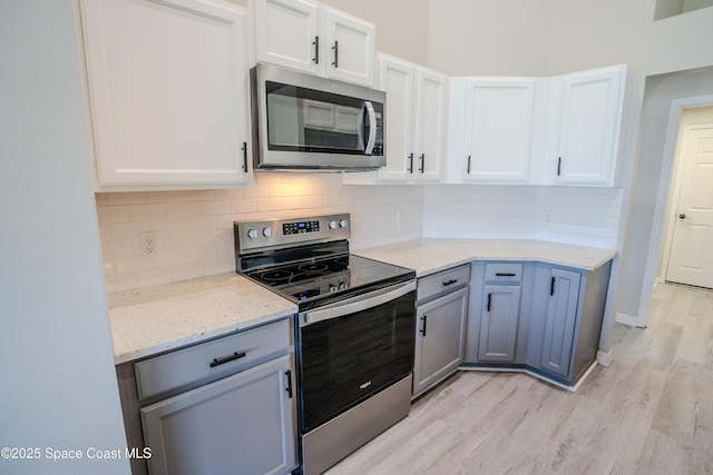 3780 Starlight Ave, Merritt Island, FL 32953 - kitchen with light stone countertops, light wood-style floors, white cabinetry, and appliances with stainless steel finishes