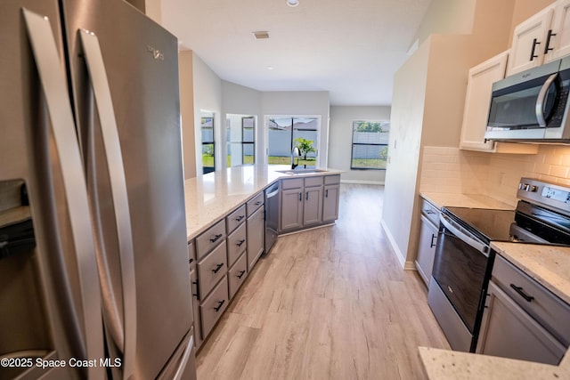 3780 Starlight Ave, Merritt Island, FL 32953 - kitchen with baseboards, appliances with stainless steel finishes, light wood-style floors, light stone countertops, and backsplash