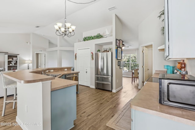 kitchen with visible vents, a notable chandelier, light wood-type flooring, stainless steel appliances, and high vaulted ceiling