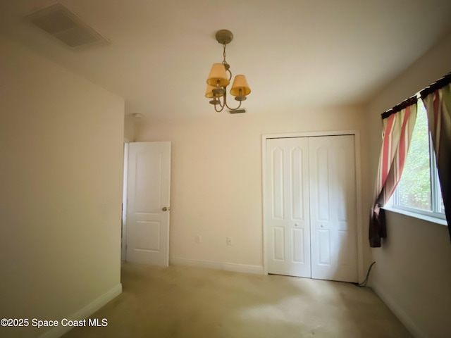 1422 Kaslo Cir NW, Palm Bay, FL 32907 - unfurnished bedroom with a chandelier, baseboards, a closet, and light colored carpet