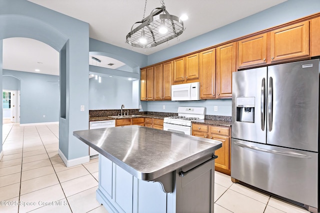 8657 Villanova Dr Unit 901, Cape Canaveral, FL 32920 - kitchen featuring white appliances, a kitchen island, light tile patterned flooring, arched walkways, and a sink