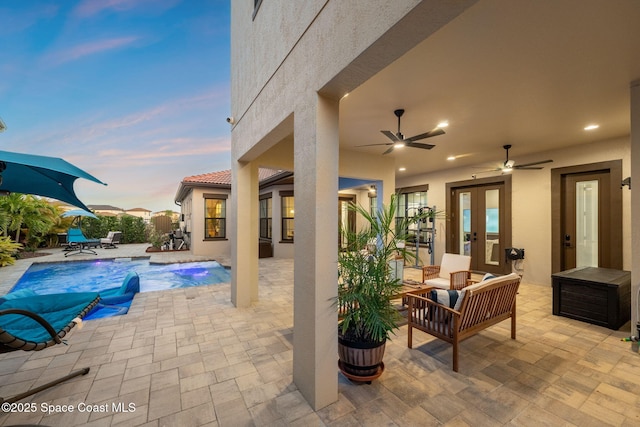 pool at dusk featuring an outdoor living space, an outdoor pool, french doors, a ceiling fan, and a patio area
