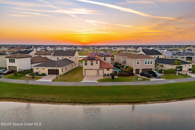 aerial view at dusk featuring a water view and a residential view