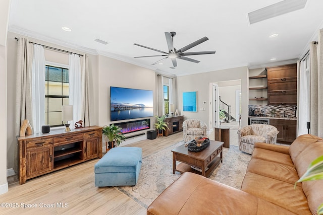 living area with light wood finished floors, visible vents, ornamental molding, and ceiling fan
