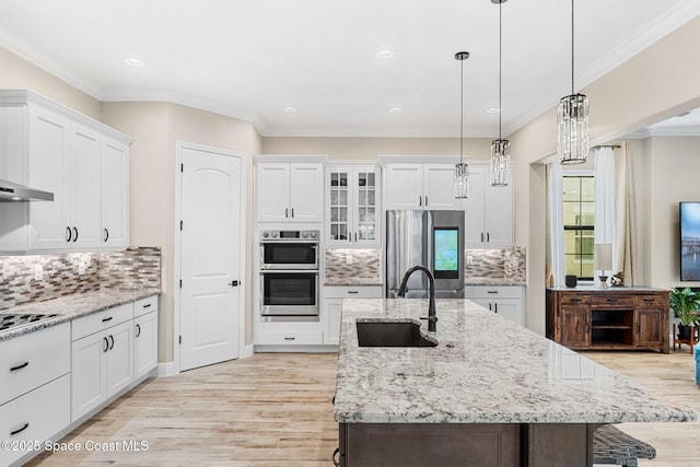 kitchen featuring light wood-type flooring, white cabinets, a center island with sink, appliances with stainless steel finishes, and a sink