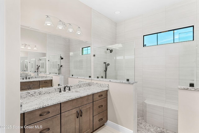 full bathroom featuring a walk in shower, two vanities, a sink, and a healthy amount of sunlight