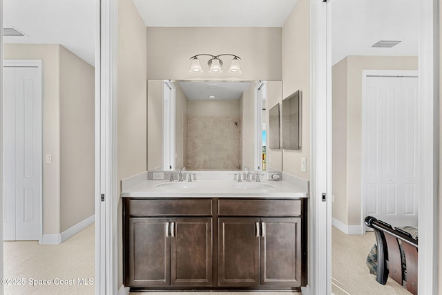 bathroom with a sink, visible vents, a tile shower, and double vanity