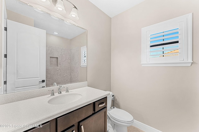 full bathroom featuring toilet, vanity, baseboards, and a healthy amount of sunlight