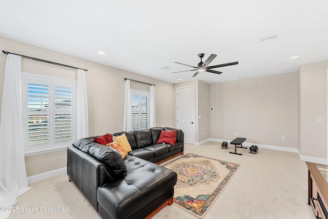 living room featuring light colored carpet, baseboards, a ceiling fan, and visible vents