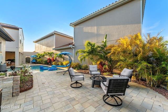 view of patio / terrace featuring a fenced in pool and a fire pit