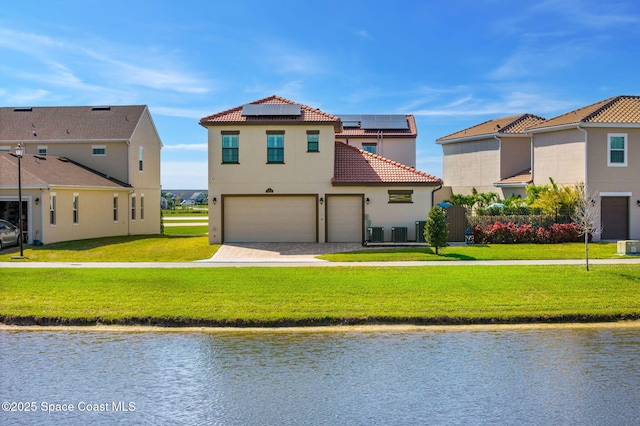 view of front of property featuring a water view, a tile roof, a front lawn, and stucco siding