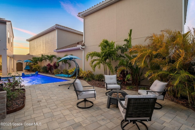 exterior space featuring a fenced in pool, a patio area, and an outdoor fire pit