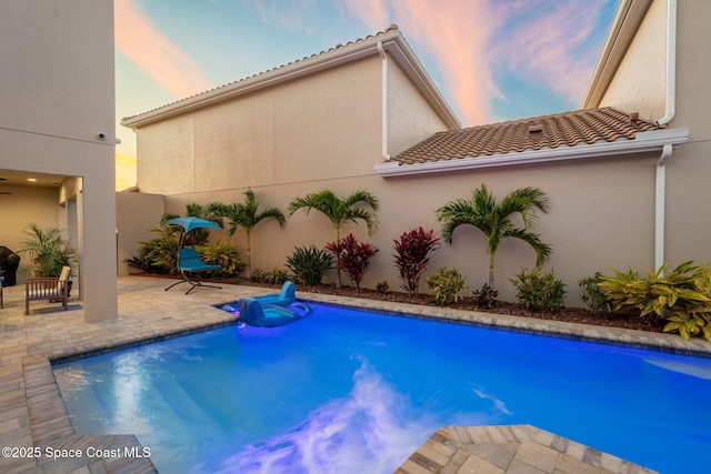 pool at dusk with a patio