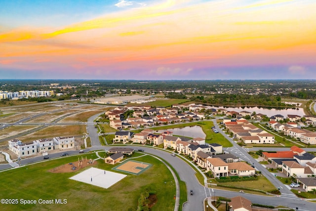 aerial view at dusk with a residential view and a water view