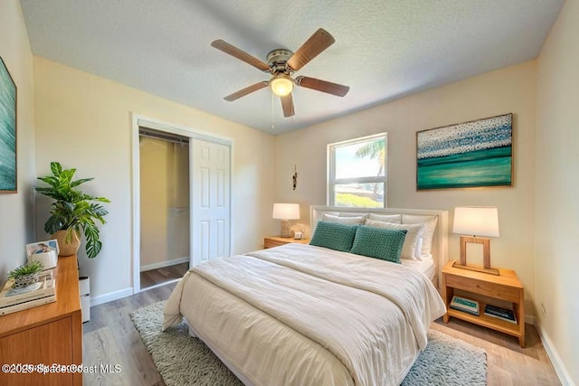 bedroom featuring a closet, baseboards, a ceiling fan, and light wood-style floors