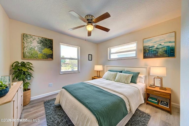 bedroom with a ceiling fan, baseboards, and light wood-style flooring