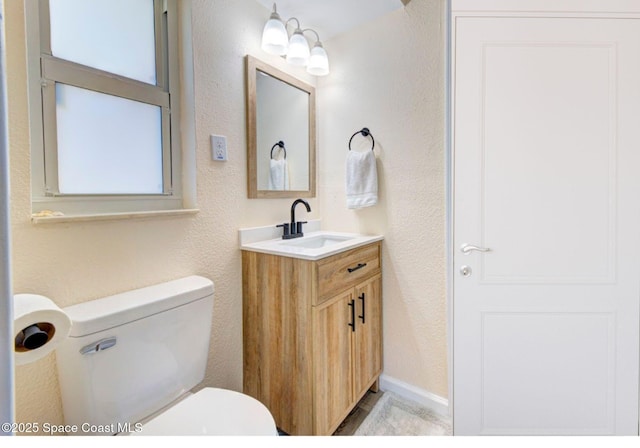 bathroom featuring vanity, a textured wall, and toilet
