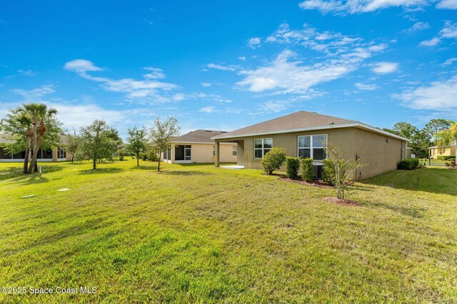 back of house with a lawn and stucco siding
