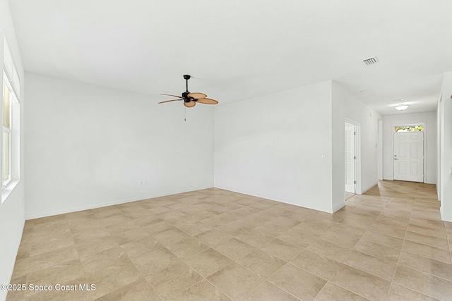 empty room featuring ceiling fan, baseboards, visible vents, and plenty of natural light